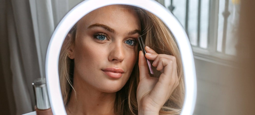 Ung kvinna framför makeup-spegel
